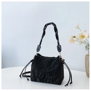 Detail of black drawstring bucket bag with pleated texture and woven wide handle