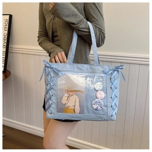 Light blue large ita bag featuring transparent window and ribbon bow details with badges