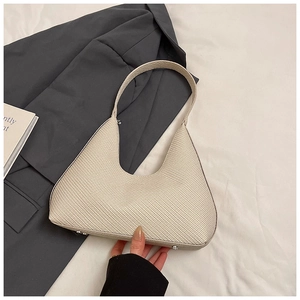 Gros plan d'un sac hobo tressé beige avec rivets métalliques sur un fond minimaliste