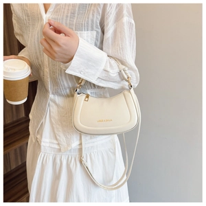 Close-up of cream leather saddle bag with gold logo and stylish knotted handle detail