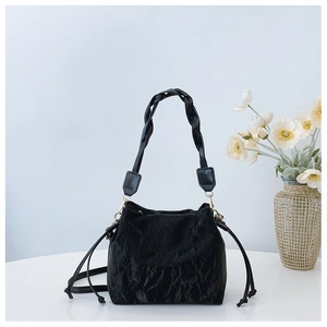 Detail of black pleated bucket bag featuring woven handle and gold-tone hardware
