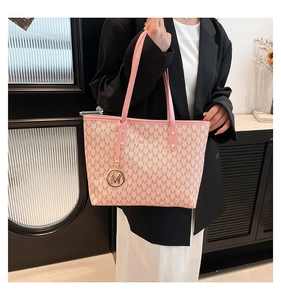 Close-up of pink tote bag featuring 'M' letter print and golden logo charm detail