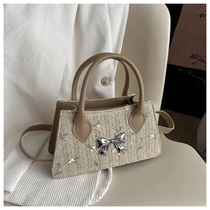 Detailed straw woven handbag with floral embroidery and a decorative silver metal bow