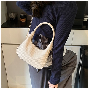 Close-up of beige woven texture bag with gold chain strap and embossed fashion logo