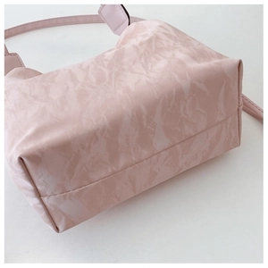 Detail of pink fashion bucket bag featuring marble texture and adjustable shoulder strap