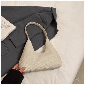 Vue détaillée du sac hobo tressé beige en forme de lune avec rivets en métal