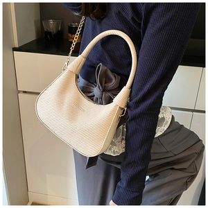 Detail of the woven texture and golden chain on a creamy white crescent shoulder bag