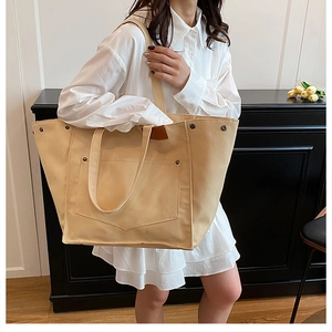 Détail du sac cabas en toile avec rivets métalliques, finitions cuir et poche frontale