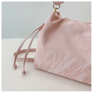 Detailed macro view of the pleated pink glossy leather texture and gold metal hooks