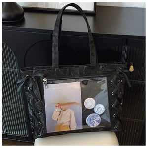 Detail of black tote bag with ribbon bow and transparent window for badges and pins