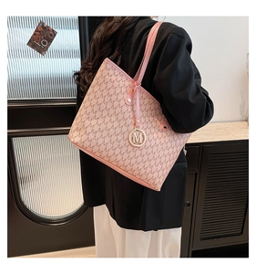 Close-up of pink tote bag with M-pattern print, golden logo charm and spacious leather body