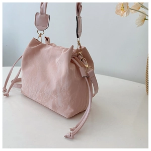 Detail of light pink bucket bag showing pleated texture and gold metal hardware