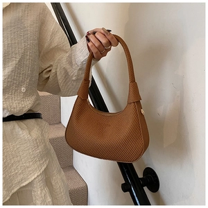Detail of a brown woven texture shoulder bag in a retro half-moon shape with a wide strap