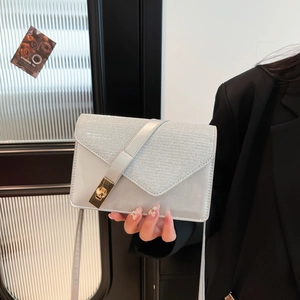 Detail of silver envelope bag showing matte texture, silk fabric, and golden metal lock