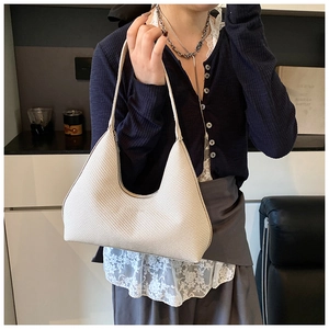 Détail de la texture tissée blanc crème sur un sac sous le bras en forme de croissant
