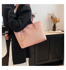 Detailed view of pink tote bag with M-letter monogram and golden logo charm