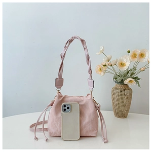 Pink pleated bucket bag with woven handle shown next to a smartphone for size reference