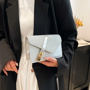 Detail of silver sequin envelope bag with gold metal lock and chic asymmetrical flap