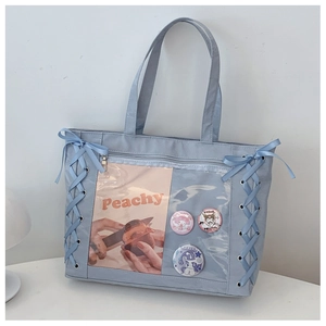 Close-up of the light blue ita bag's transparent window with badges and ribbons