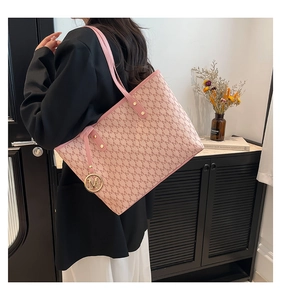 Detailed macro view of pink tote bag featuring letter M monogram and golden metal charm