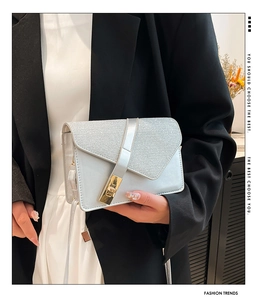 Close-up of silver crossbody bag featuring a geometric flap and gold metal clasp lock