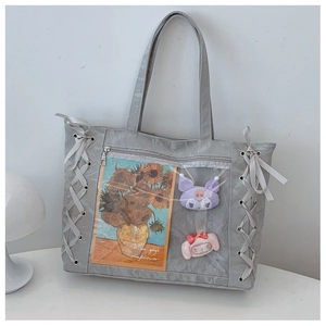Detail of grey ita bag featuring ribbon lace-up sides and clear PVC window for display