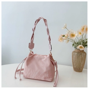Detail of light pink pleated cloud bucket bag with woven handle and gold metal hardware