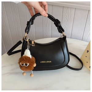 Detail of black PU leather hobo bag with knotted handle and brown monster plush charm