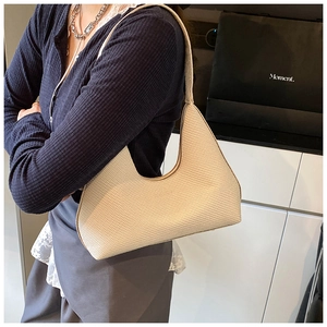 Vue détaillée d'un sac porté épaule beige tressé montrant sa texture et sa forme de lune