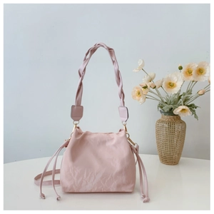 Close-up of pink drawstring bucket bag with pleated texture and stylish woven handle