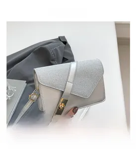 Detail of silver crossbody bag with textured flap and golden twist-lock closure