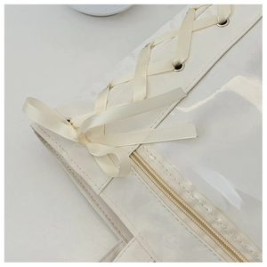 Close-up of a white ita bag with satin ribbon lacing and clear PVC window detail