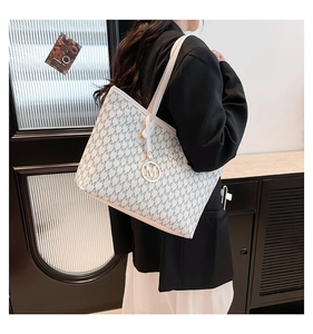 Detail of printed tote bag with round gold M-logo charm and grey monogram pattern