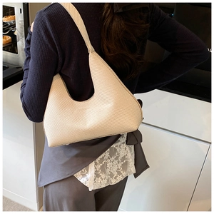 Gros plan du sac hobo tissé crème montrant la texture détaillée et la forme demi-lune