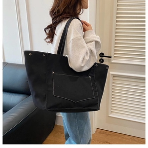Détail d'un grand cabas en toile noire avec surpiqûres blanches et rivets métalliques
