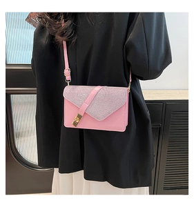 Model wearing a pink crossbody bag with glitter flap and gold clasp on a black blazer