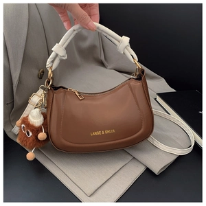 Close-up of a brown semi-circle saddle bag with white knotted handle and plush charm