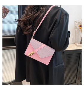 Pink crossbody bag with glitter texture flap and gold lock shown on a black suit