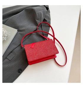 Detail of red crossbody bag with textured glitter flap on dark grey suit background