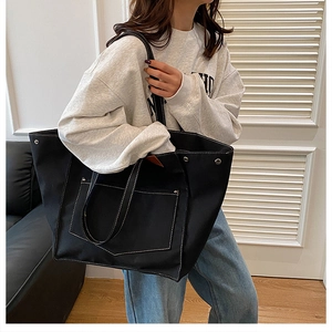 Détail d'un grand sac cabas en toile noire avec des surpiqûres blanches contrastées
