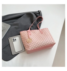 Detail of pink monogram tote bag with gold M charm and smartphone for size comparison
