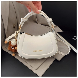 Detail of white PU saddle bag featuring a knotted handle and brown bear charm