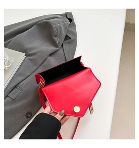 Detail of red small flap bag showing gold magnetic closure and black inner lining