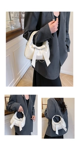 Close-up of white half-moon bag featuring a large bow detail and metallic chain strap