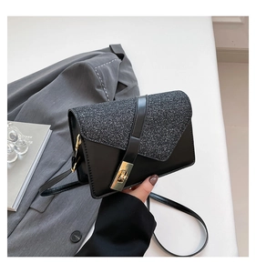 Detail of black PU leather crossbody bag with silver glitter flap and gold snap button