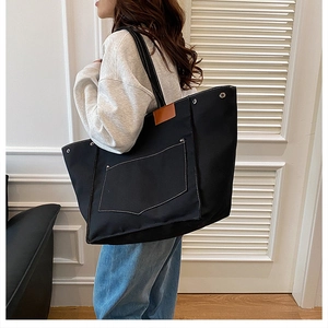 Détail du grand sac cabas noir en toile avec poche frontale et coutures blanches contrastées