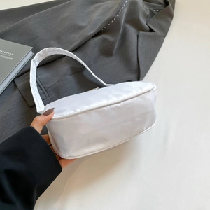 Detailed texture of white satin shoulder bag placed on a grey formal blazer