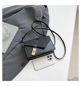 Detail of black sequin crossbody bag with gold twist lock next to a smartphone