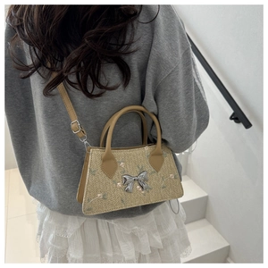 Detail of woven straw bag with floral embroidery and silver metal bow ornament