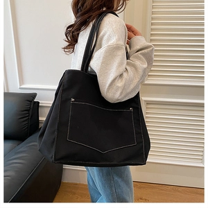 Gros plan du sac cabas en toile noire avec coutures contrastées et rivets
